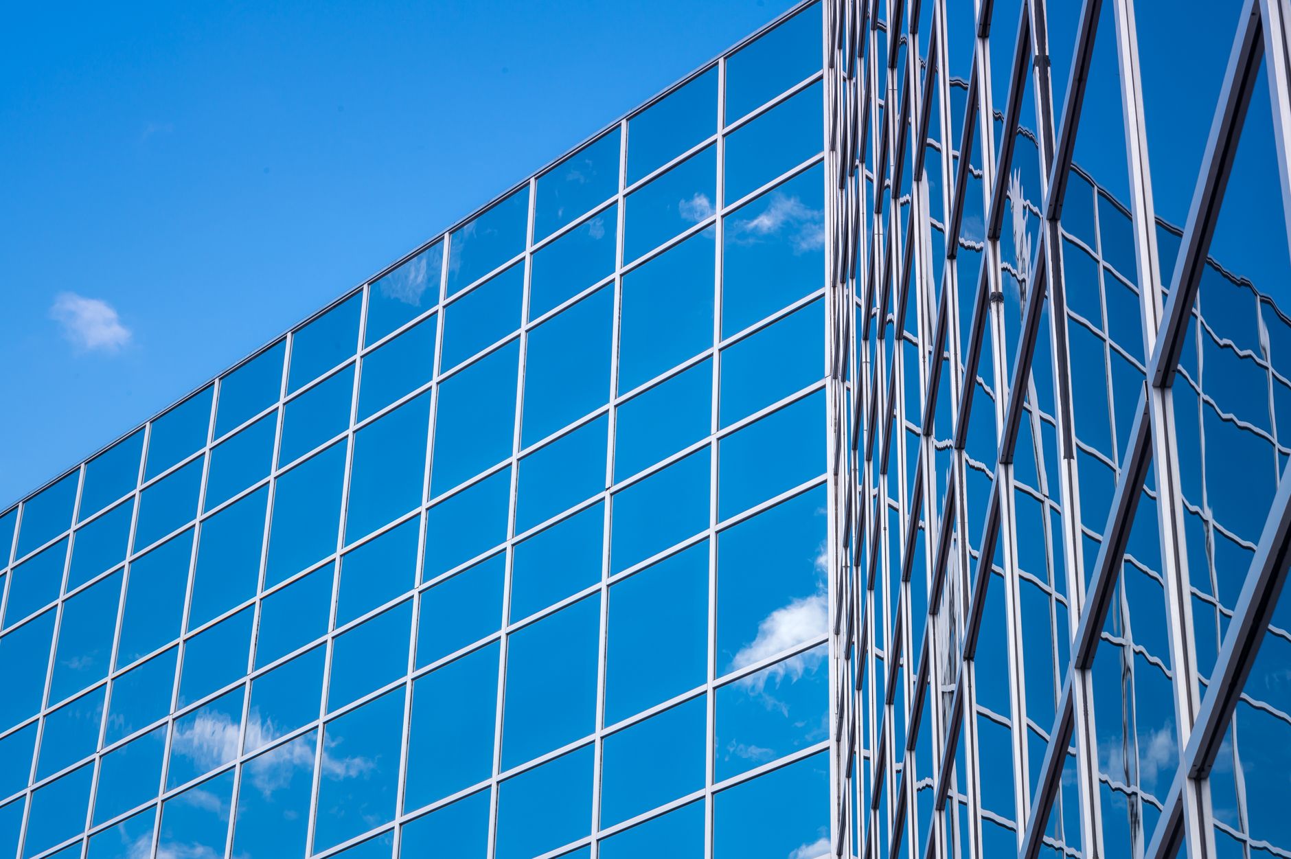 A glass facade reflecting the sky above a downtown street