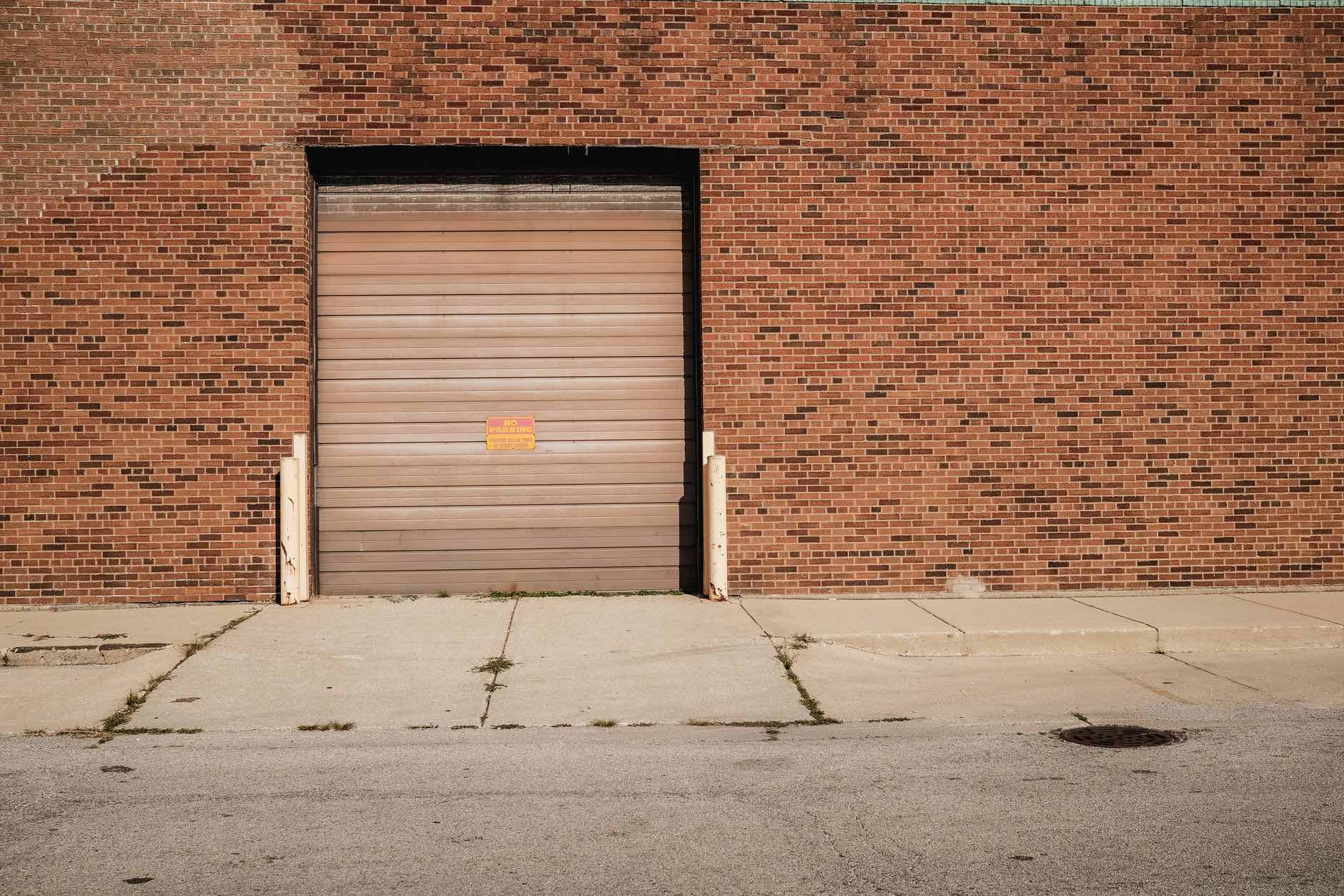 A single loading door set into a plain brick wall above a concrete apron