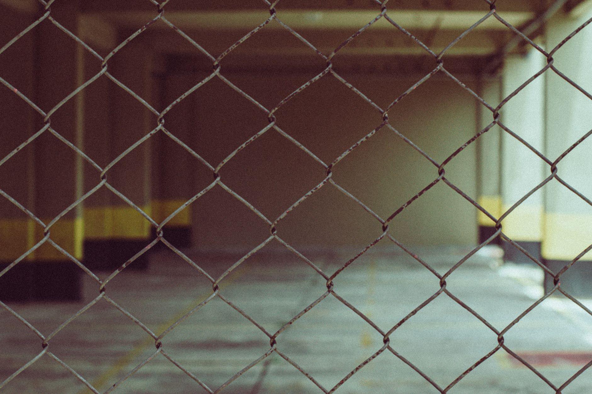 A chain link fence in close focus, with a covered service area beyond it