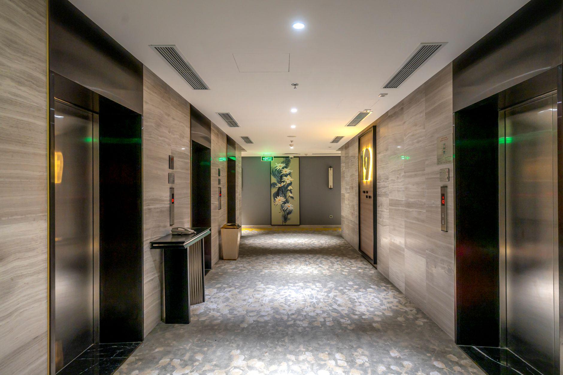 An empty elevator lobby with stone walls and elevator doors on both sides
