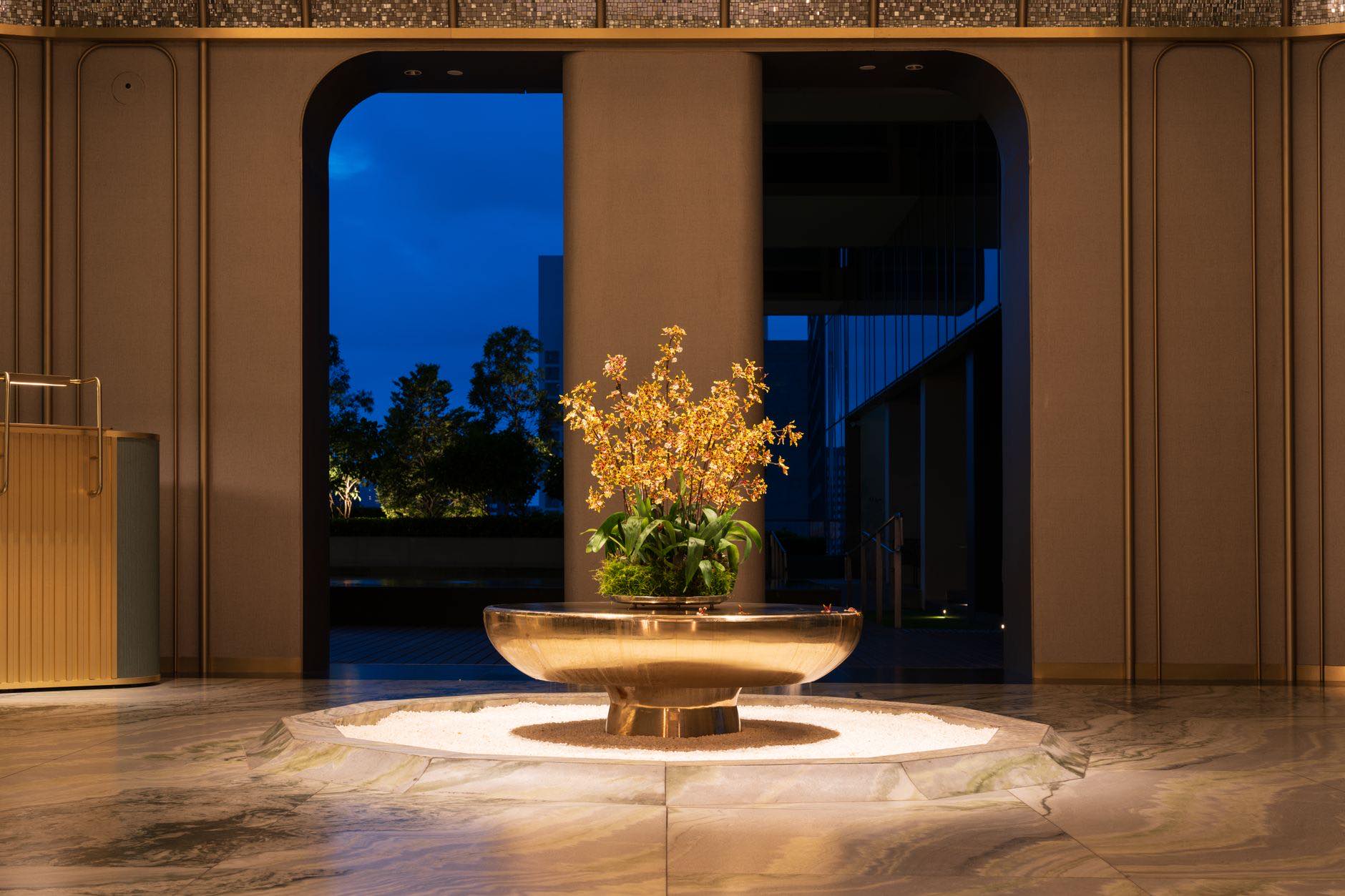 A dark lobby interior with a lit planter bowl standing on a stone floor