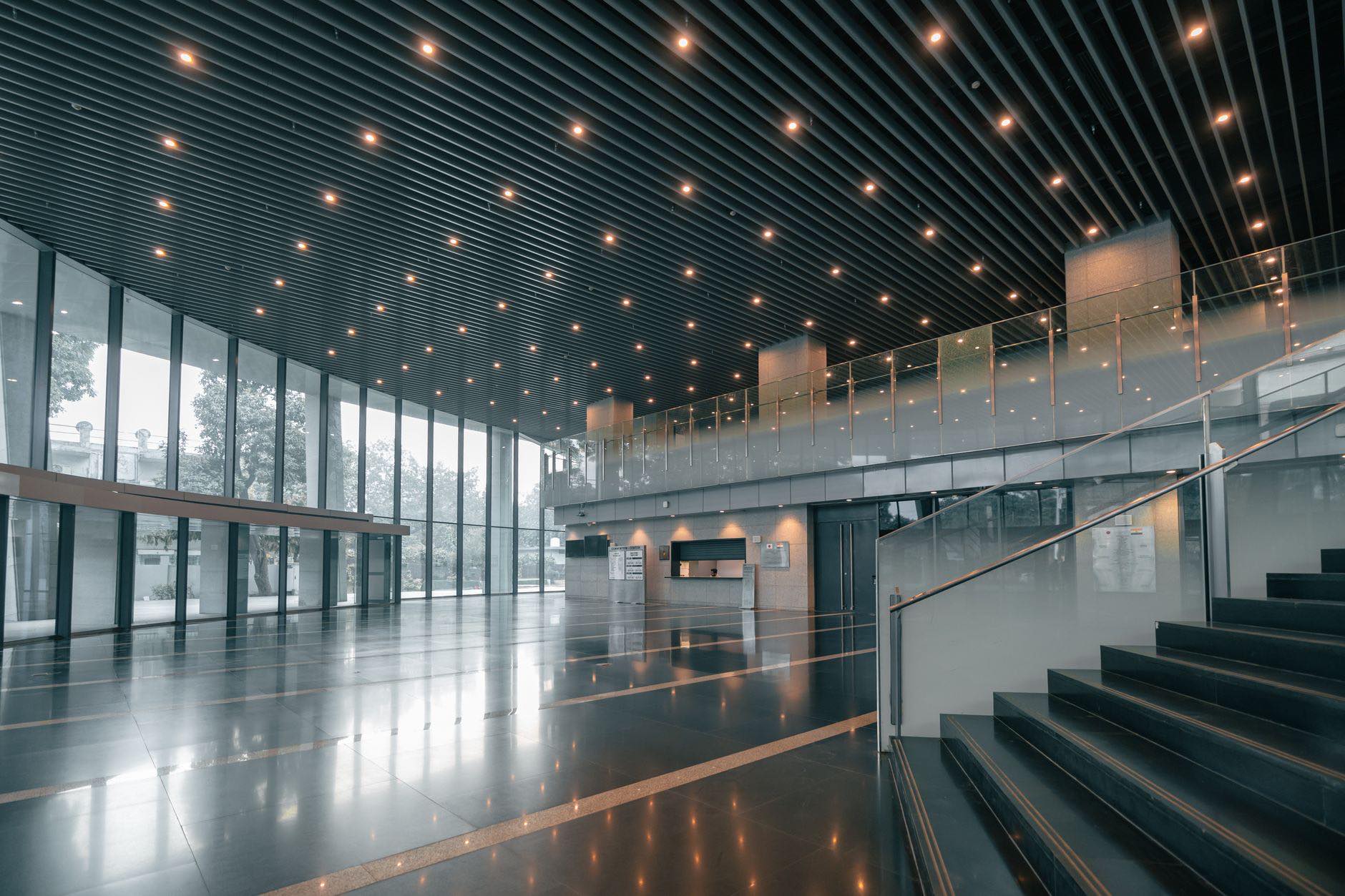 A glass walled lobby with a wide staircase and a polished floor
