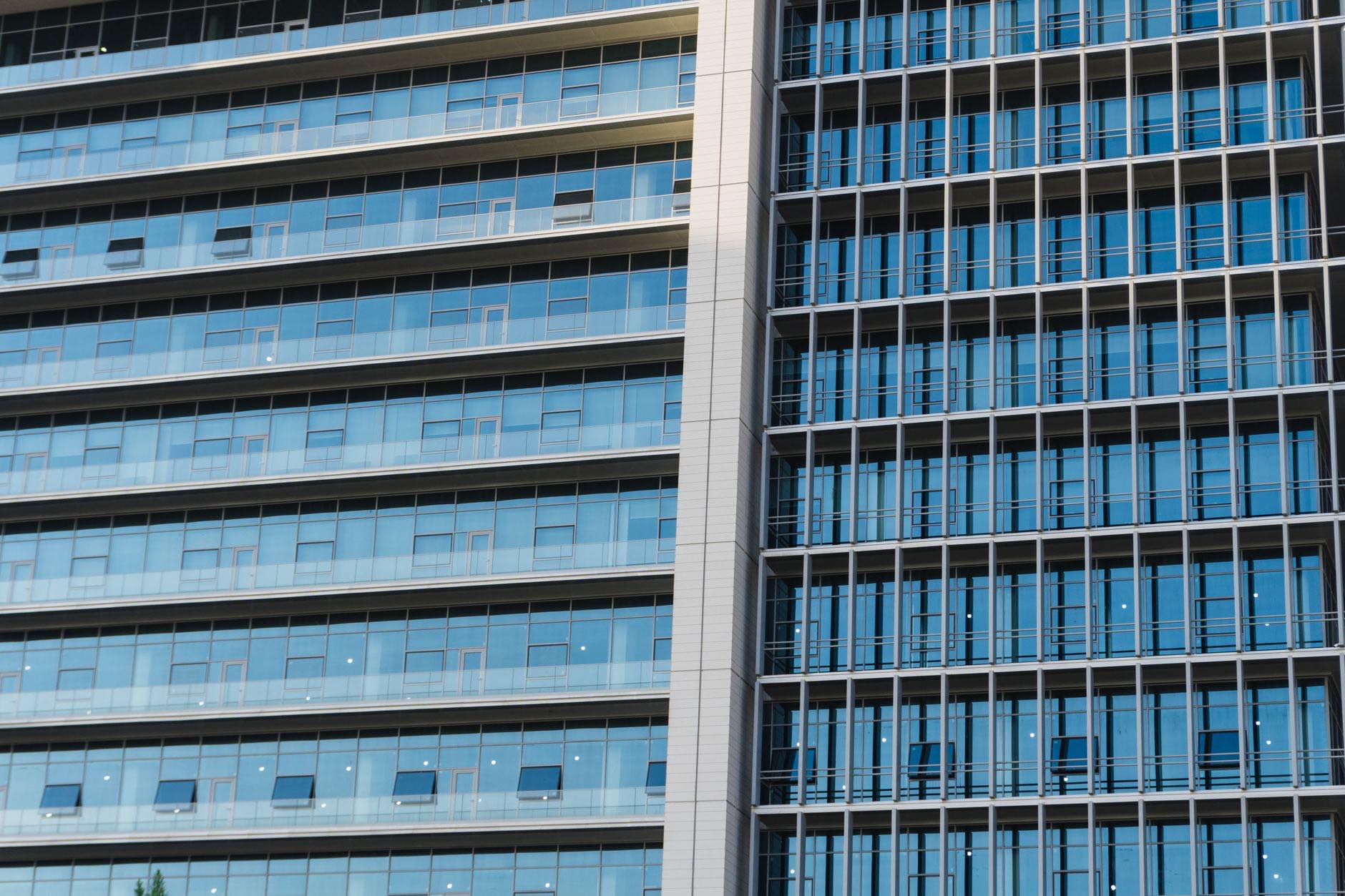 Two building facades of gridded window bays, seen close and from below