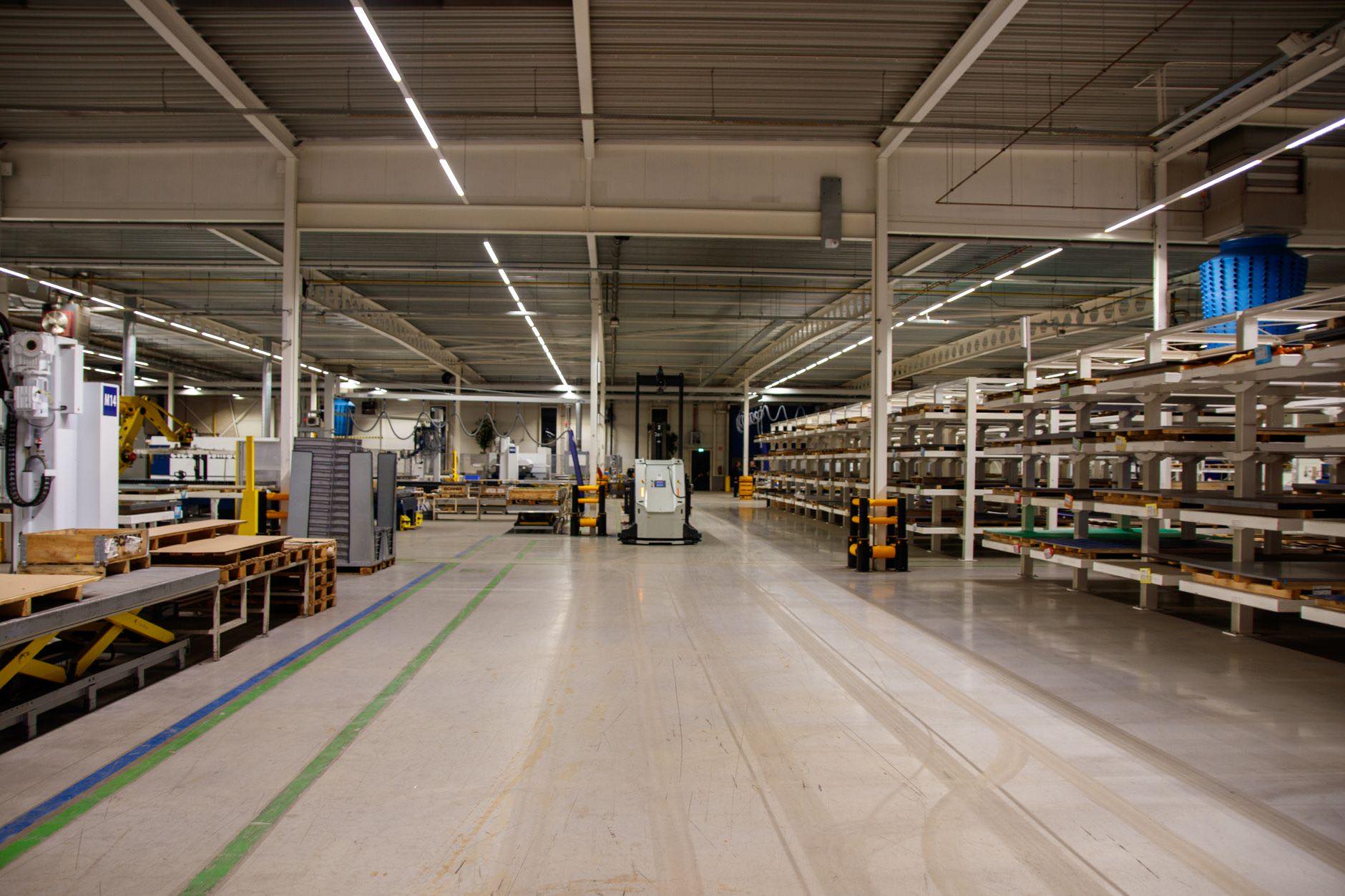 A warehouse aisle between tall storage racking, lit from overhead